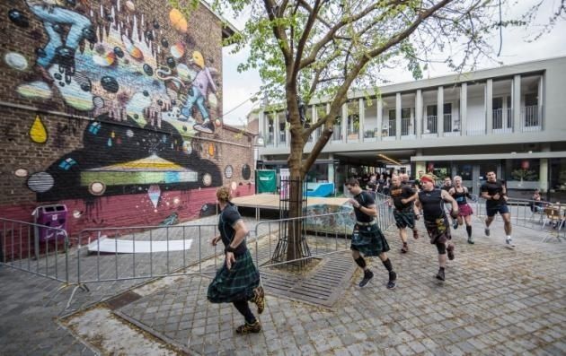 Straatkunstmuur naast een binnenplaats waar doedelzakspelers lopen